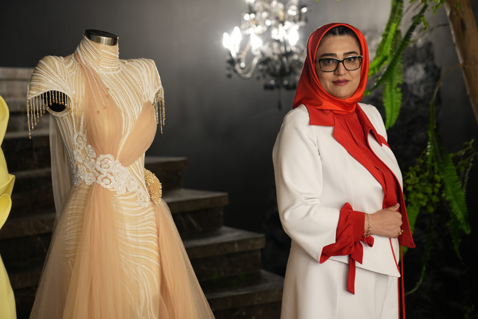 ملیحه ظریفیان کنار لباس مجلسی دوخته‌شده با تور و گیپور روی مانکن